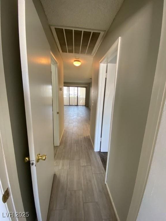 hall featuring baseboards, visible vents, and wood tiled floor