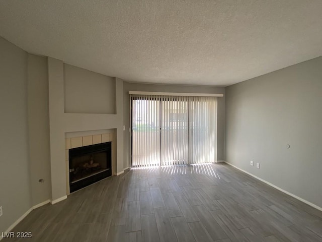 unfurnished living room with a tile fireplace, wood finished floors, and baseboards