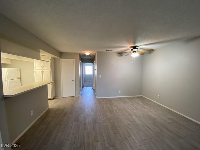 unfurnished room featuring a textured ceiling, ceiling fan, dark wood-style flooring, visible vents, and baseboards