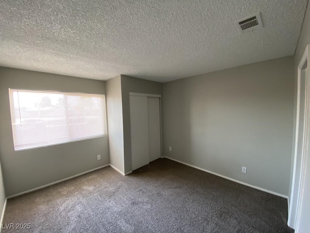 unfurnished bedroom featuring a closet, visible vents, dark carpet, and baseboards