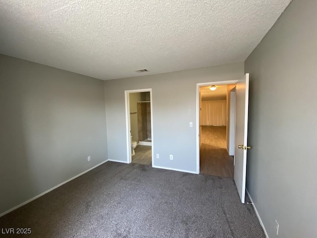 unfurnished bedroom with a textured ceiling, dark carpet, visible vents, and baseboards