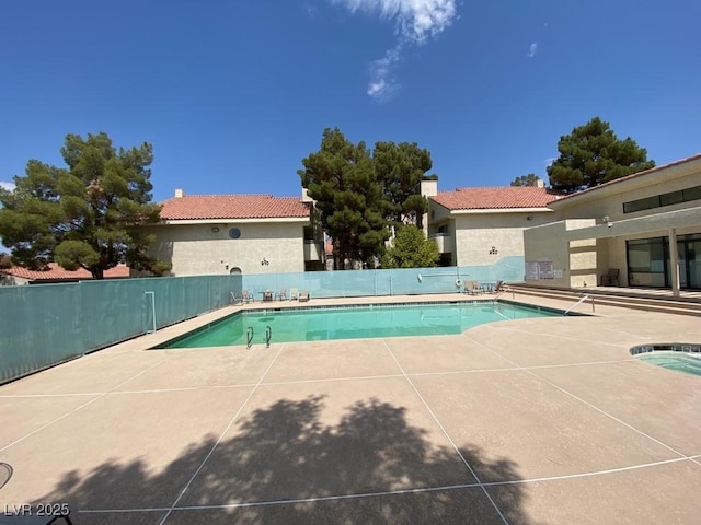 community pool with a patio area and fence