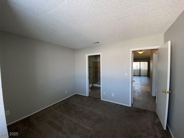 unfurnished bedroom featuring a textured ceiling, dark colored carpet, visible vents, and baseboards