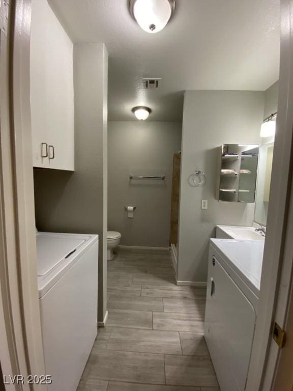 bathroom featuring toilet, visible vents, washer and dryer, and vanity