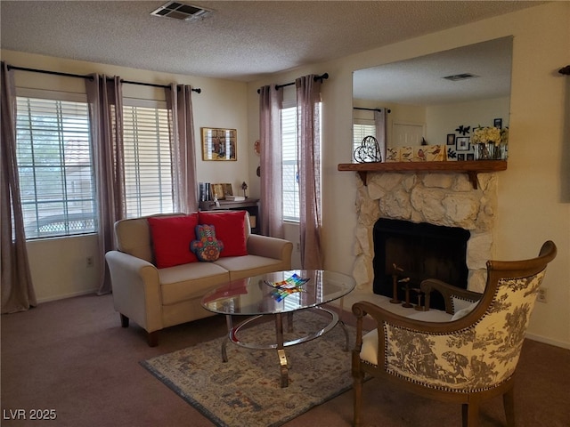 living room with a textured ceiling, a fireplace, carpet flooring, and visible vents