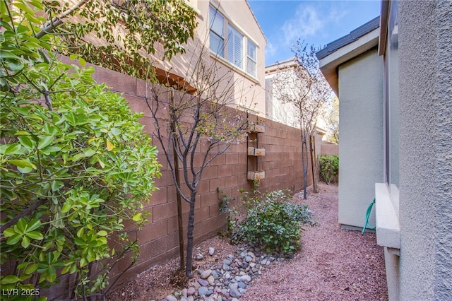 view of side of home with a fenced backyard and stucco siding