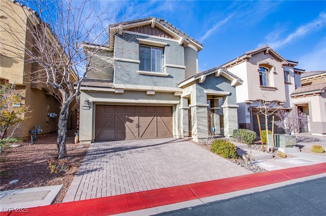 view of front of house featuring decorative driveway, an attached garage, a tile roof, and stucco siding