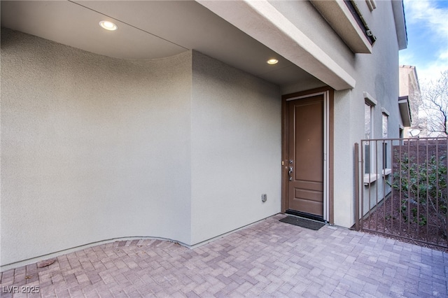 entrance to property featuring a balcony and stucco siding