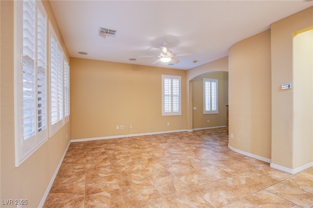 unfurnished room featuring baseboards, visible vents, arched walkways, and a ceiling fan