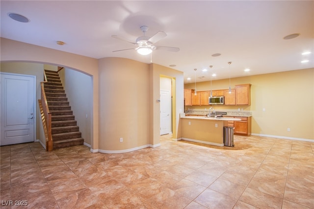 kitchen with baseboards, stainless steel microwave, light countertops, pendant lighting, and recessed lighting