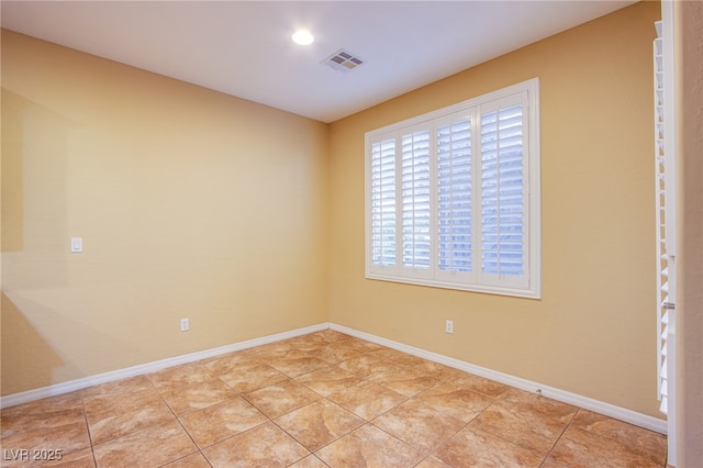 empty room with light tile patterned floors, visible vents, and baseboards