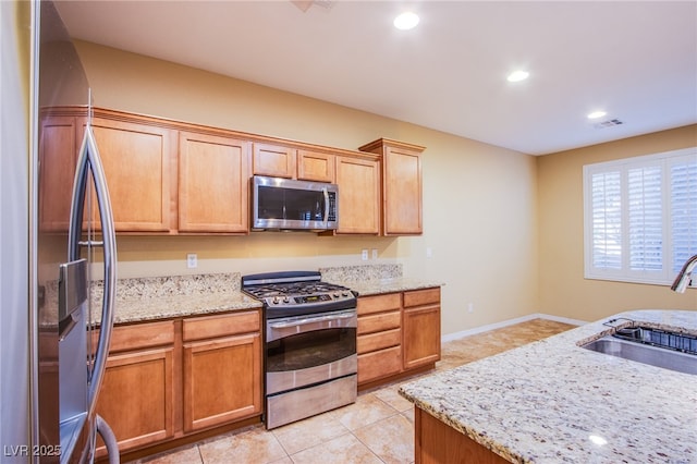 kitchen with light stone counters, stainless steel appliances, recessed lighting, light tile patterned flooring, and a sink