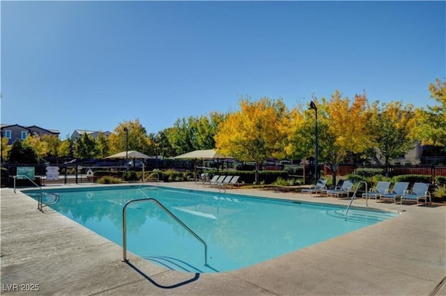 community pool with a patio area and fence