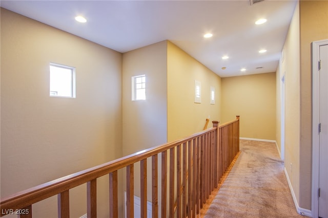 corridor with light carpet, recessed lighting, baseboards, and an upstairs landing