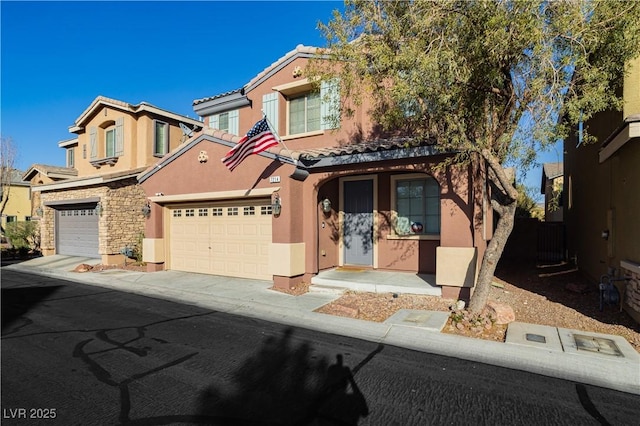 view of front of property featuring an attached garage, a tiled roof, concrete driveway, stone siding, and stucco siding