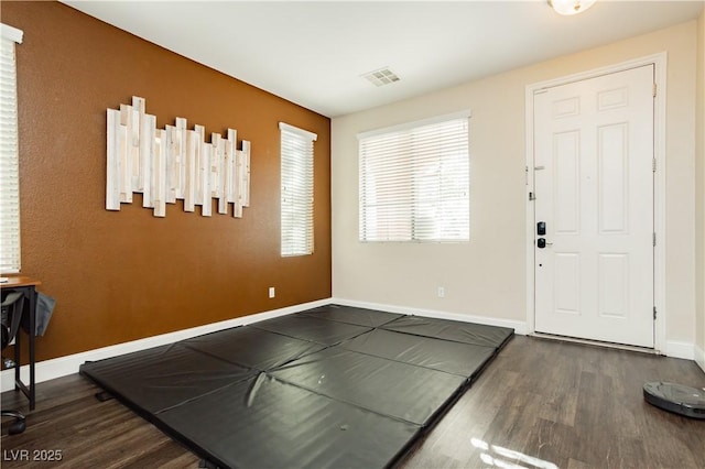 foyer entrance featuring visible vents, baseboards, and wood finished floors