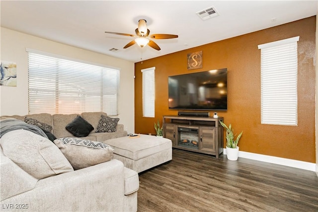 living room featuring baseboards, wood finished floors, visible vents, and a ceiling fan