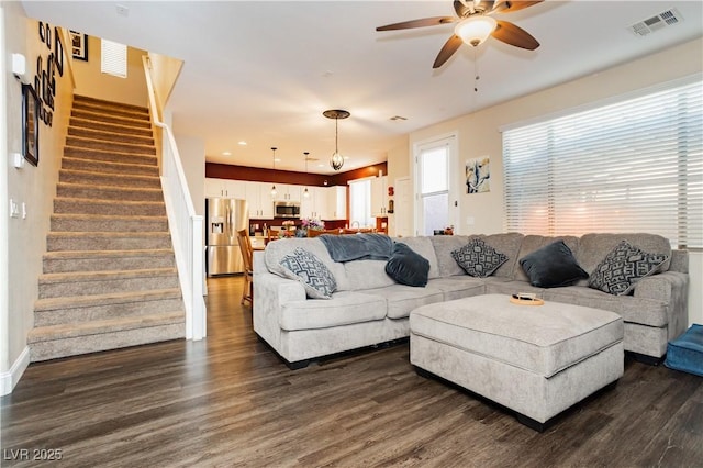 living room with ceiling fan, stairway, dark wood finished floors, and visible vents