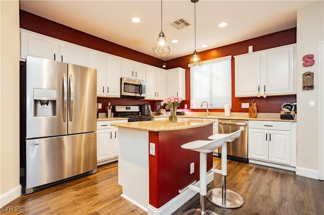 kitchen featuring visible vents, white cabinets, dark wood finished floors, appliances with stainless steel finishes, and a center island