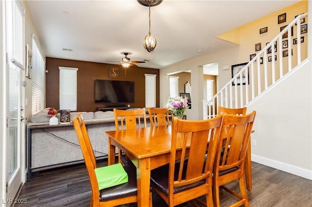 dining area featuring visible vents, baseboards, a ceiling fan, wood finished floors, and stairs