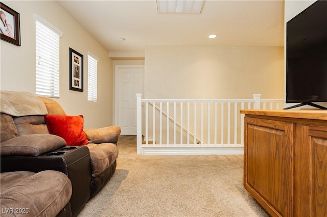 living area with recessed lighting, visible vents, light colored carpet, and an upstairs landing