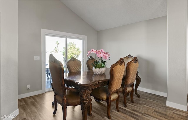 dining space featuring lofted ceiling, baseboards, and wood finished floors