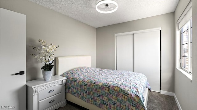 bedroom with a textured ceiling, a closet, dark carpet, and baseboards