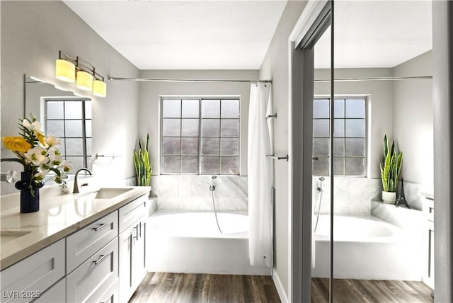 full bath featuring double vanity, a shower, wood finished floors, a sink, and a bath