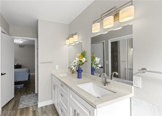 full bath with double vanity, visible vents, a sink, and wood finished floors