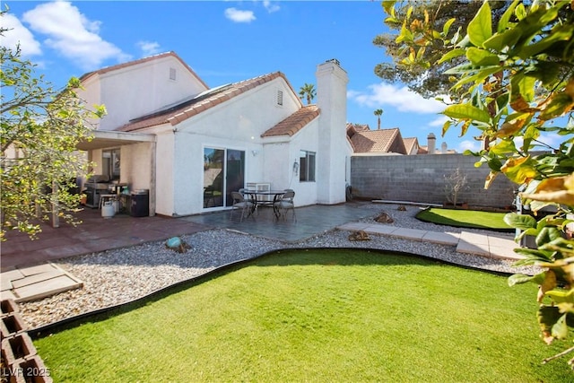 rear view of property with a lawn, a patio, a fenced backyard, a chimney, and stucco siding