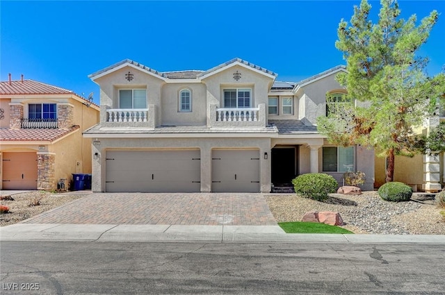 mediterranean / spanish house with a tile roof, an attached garage, decorative driveway, roof mounted solar panels, and stucco siding