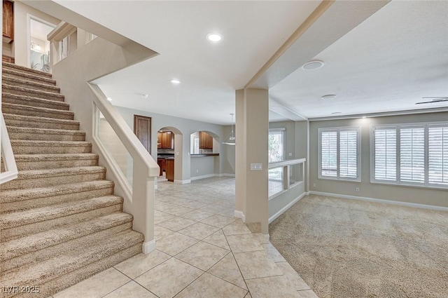 entrance foyer featuring arched walkways, baseboards, light colored carpet, light tile patterned flooring, and recessed lighting