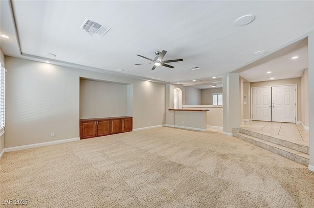 unfurnished living room featuring baseboards, visible vents, ceiling fan, and light colored carpet