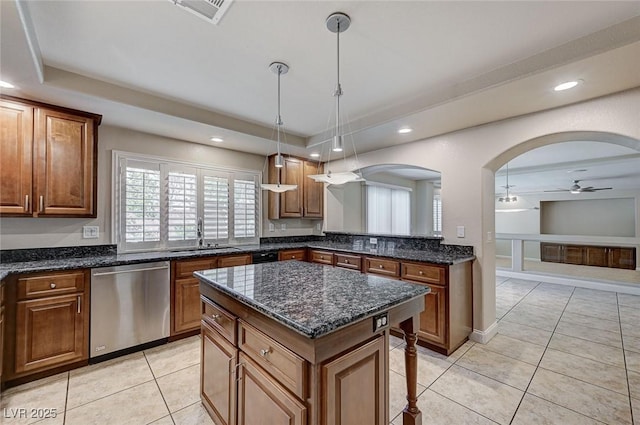 kitchen featuring a sink, stainless steel dishwasher, arched walkways, and a raised ceiling