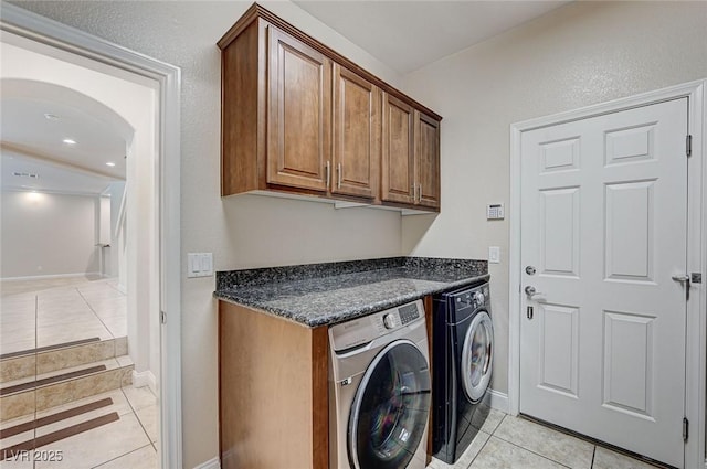 washroom featuring independent washer and dryer, light tile patterned flooring, cabinet space, and baseboards