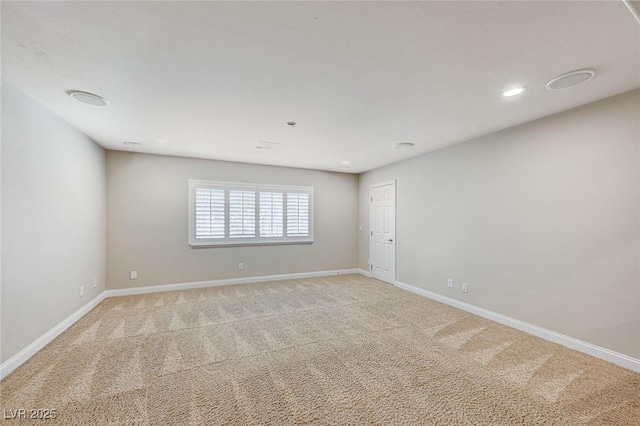 spare room featuring light carpet and baseboards