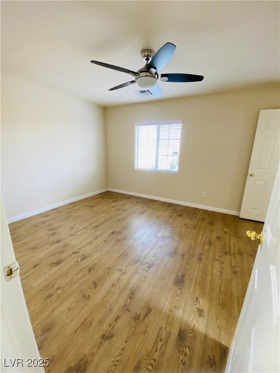 empty room featuring a ceiling fan, visible vents, baseboards, and wood finished floors