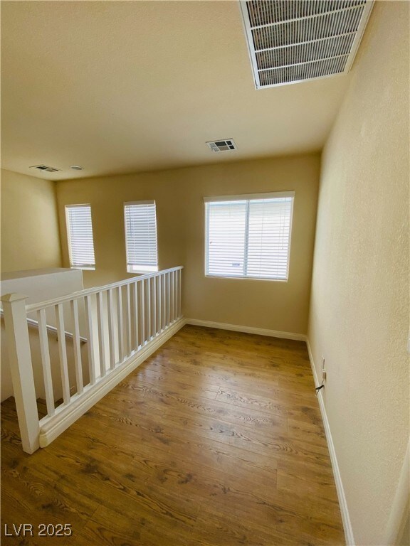 unfurnished room with visible vents, baseboards, and wood finished floors