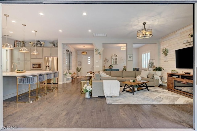 living room with wood finished floors, visible vents, and recessed lighting