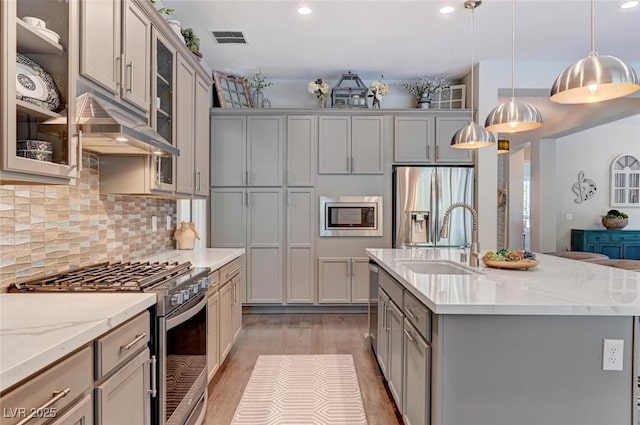 kitchen with gray cabinets, visible vents, appliances with stainless steel finishes, a sink, and under cabinet range hood