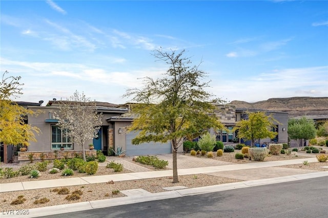 view of front of home featuring decorative driveway, an attached garage, and stucco siding