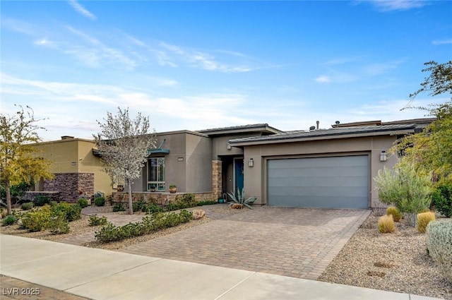 view of front of property with a garage, stone siding, decorative driveway, and stucco siding