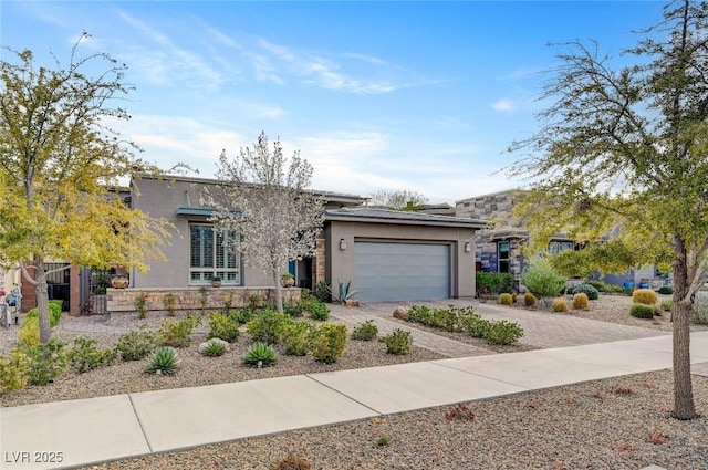 view of front of home featuring decorative driveway, stucco siding, fence, a garage, and stone siding