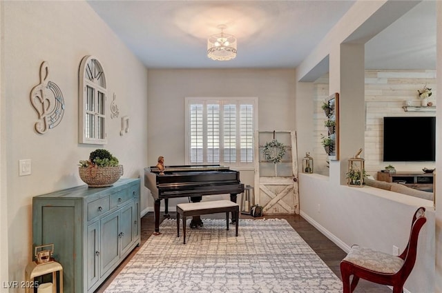 living area featuring dark wood finished floors, baseboards, and an inviting chandelier