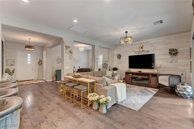 living area featuring visible vents, wooden walls, and wood finished floors