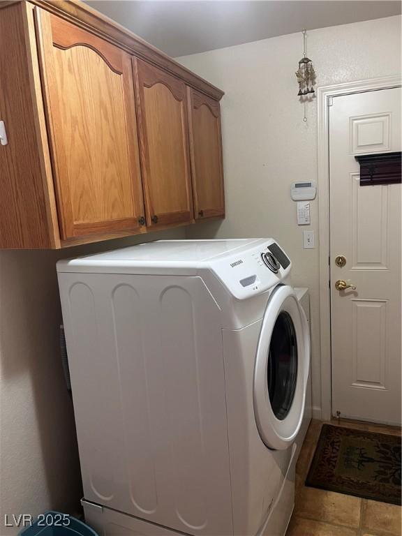 clothes washing area featuring cabinet space, washer and clothes dryer, and tile patterned floors