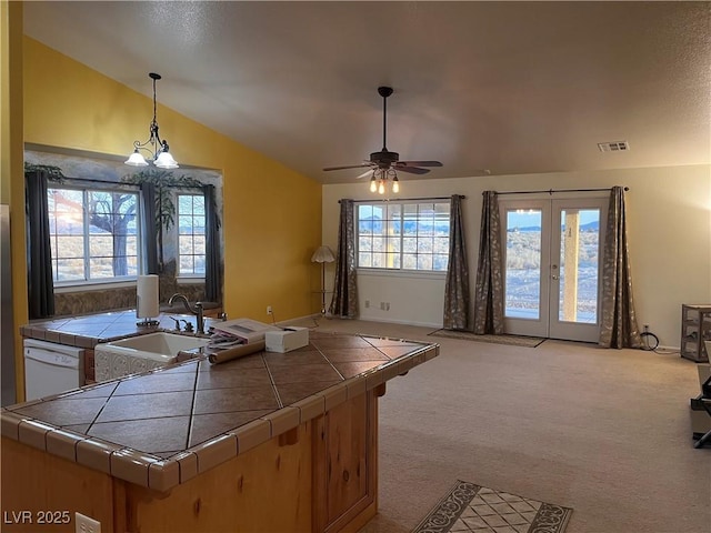 kitchen with visible vents, dishwasher, tile countertops, lofted ceiling, and a sink