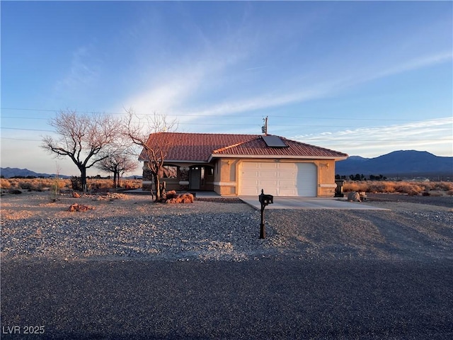 view of front of home with an attached garage, a mountain view, a tiled roof, driveway, and stucco siding