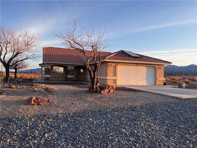 view of front of property with a garage, solar panels, concrete driveway, a tiled roof, and stucco siding