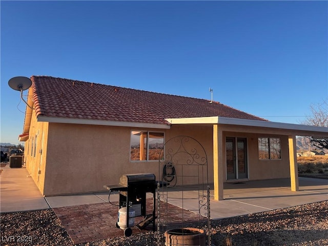 back of property with a patio area, a tiled roof, and stucco siding